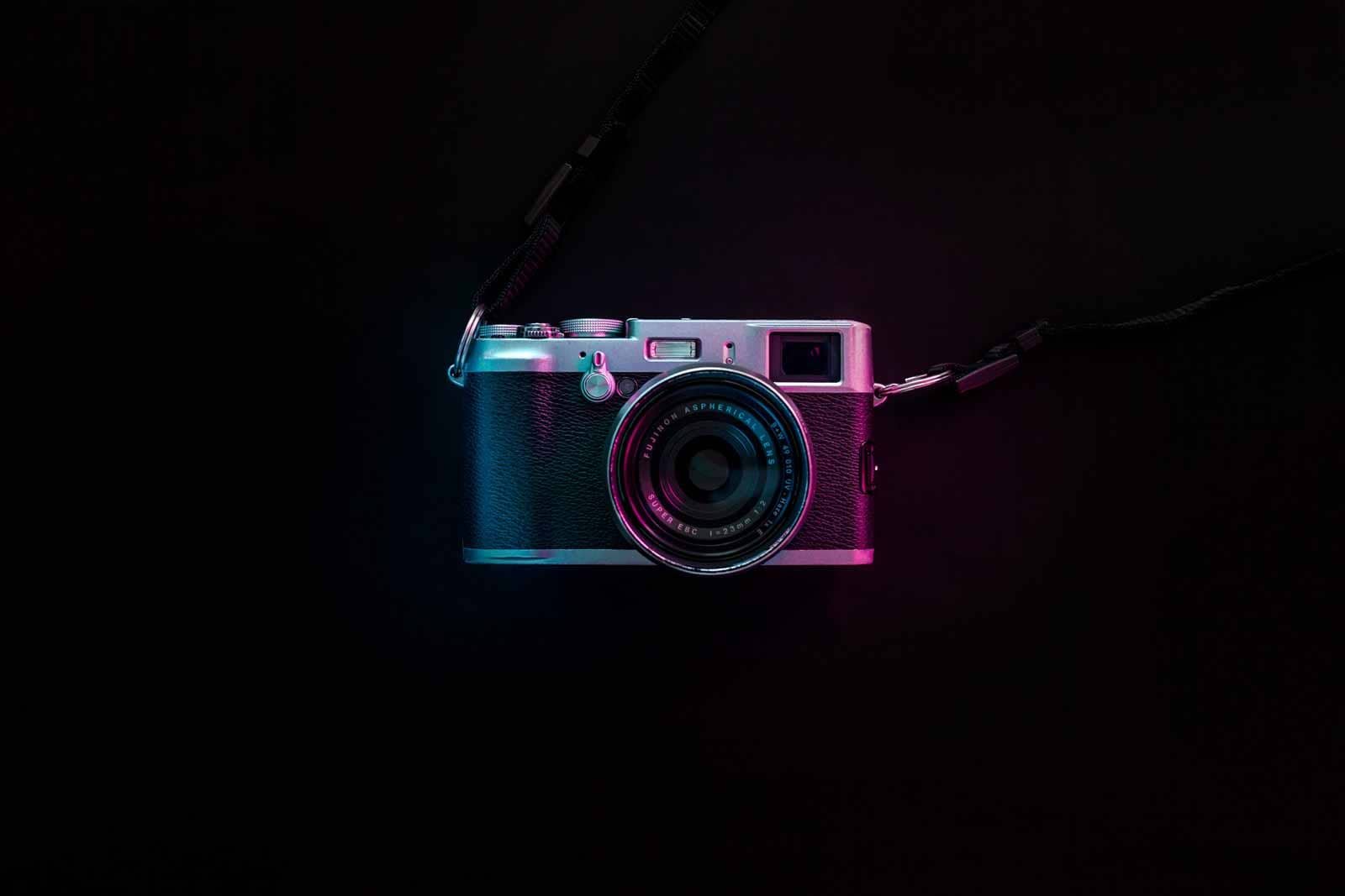 A rangefinder camera lit in pink and cyan