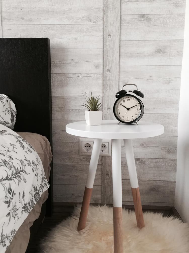 Round white bedside table with a clock