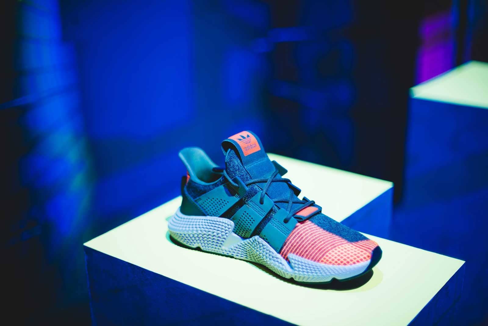 Blue and pink Prism Volt sneaker on a lit pedestal